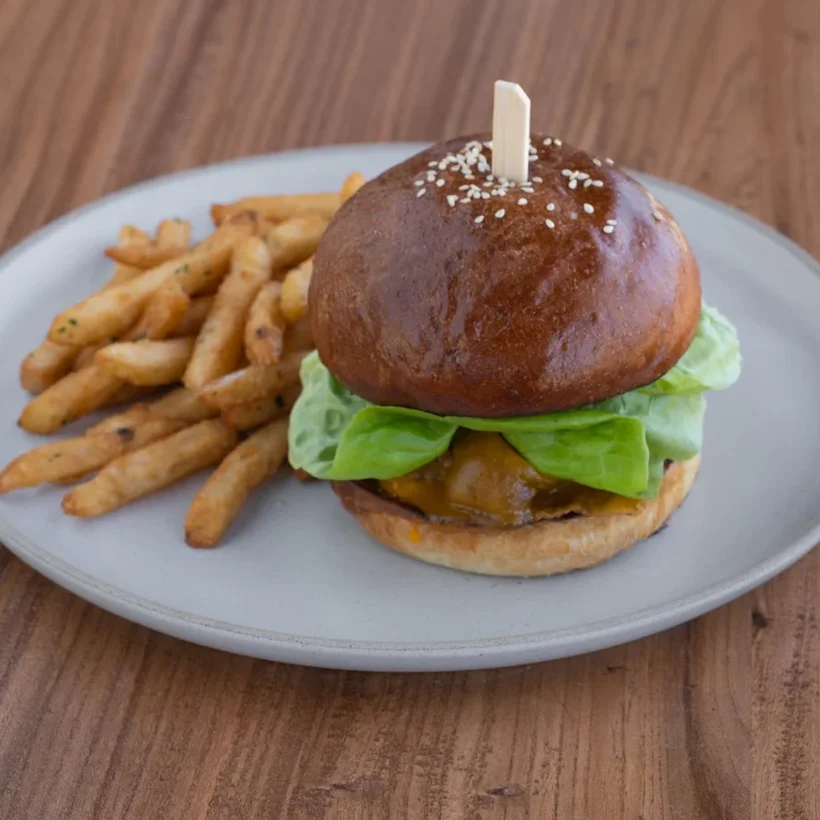 A brioche cheeseburger with butter lettuce and a side of seasoned fries